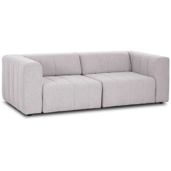 Sofa narozna o wyrazistej formie z oszczednym detalem w odcieniu bieli