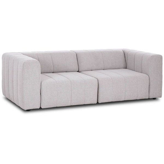 Sofa narozna o wyrazistej formie z oszczednym detalem w odcieniu bieli